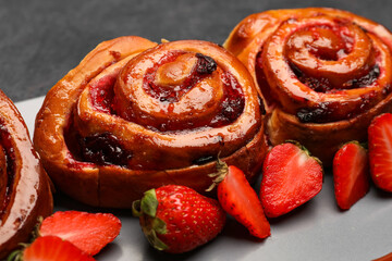 Tasty buns with strawberries on tray, closeup