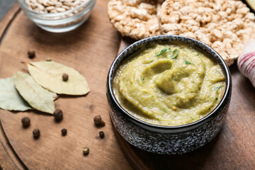 Bowl with tasty baba ghanoush and spices on wooden table, closeup