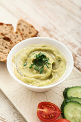 Bowl with tasty baba ghanoush, bread and vegetables on table, closeup