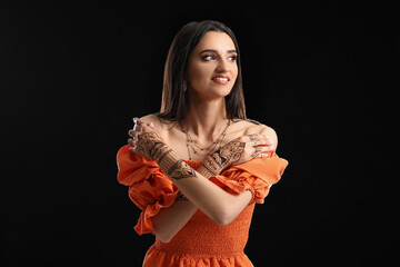 Beautiful Indian woman with henna tattoo on dark background