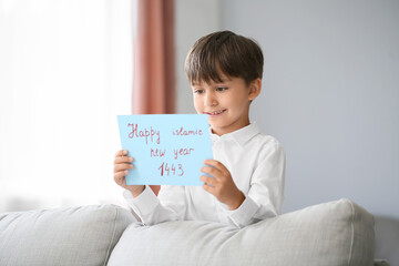 Little boy with greeting card for Islamic New Year at home