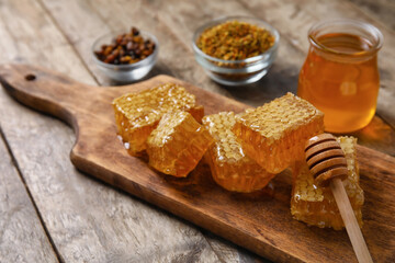 Board with honey combs on wooden background
