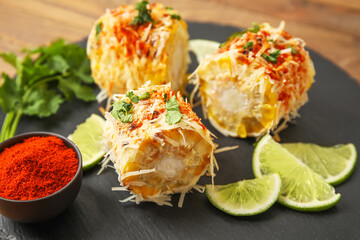 Board with pieces of tasty Elote Mexican Street Corn on table, closeup