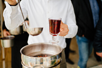 a man pours hot mulled wine into a glass. warming drink