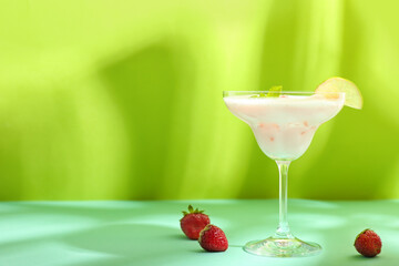 Glass of strawberry Pina Colada cocktail and berries on color background