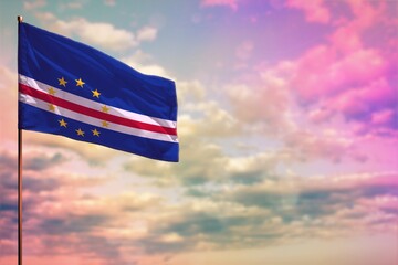 Fluttering Cabo Verde flag mockup with the space for your content on colorful cloudy sky background.