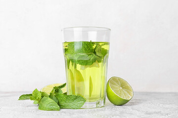 Glass of tasty mint tea with lime on white background