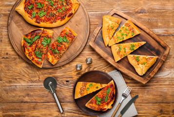 Boards and plate with tasty Turkish Pizza on wooden background