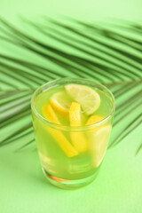 Glass with tasty lemonade on color background