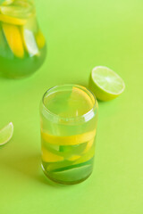 Glass and jug with tasty lemonade on color background
