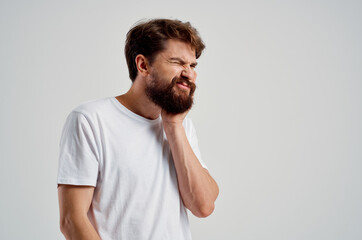 Obraz premium emotional man holding on to face pain in teeth light background