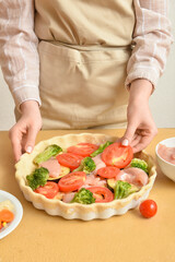 Woman preparing chicken pot pie with vegetables at kitchen table, closeup