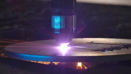 Close-up demonstration of industrial plasma laser cutting. Electric computer operated system in metalworking industry. Automated laser-cutter burns metal sheet and plates with spark flying around.