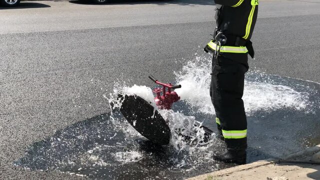 Unrecognizable russian firemen opens fire hydrant on the road