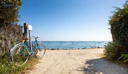 Vieux vélo bleu en bord de mer, sentier donnant sur la plage. © Thierry RYO