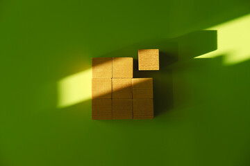 Nine wooden blocks in the form of the square on the green background with the natural shadows from...