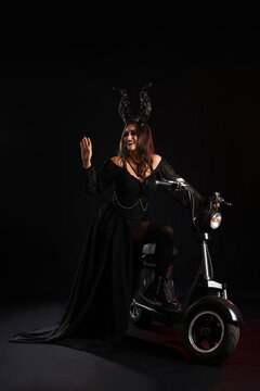 Woman dressed for Halloween with motorcycle on dark background
