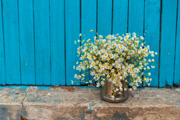 Summer bouquet of white daisies, in an iron vase, on a wooden background. High quality photo