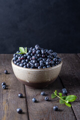 Fototapeta na wymiar Blueberry bowl on wooden background with copy space in rustic style