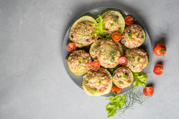 Zucchini stuffed with meat and rice with tomatoes, dill, lettuce on a round plate. 