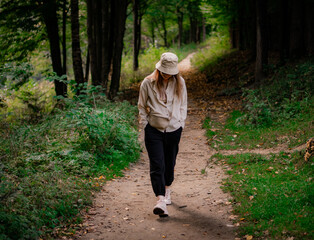 А woman in a beige hat walks through the park and laughs