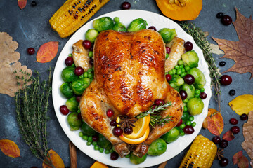 Thanksgiving turkey or chicken for a festive dinner. Food table background with autumn seasonal specialties for Thanksgiving Day. Fried chicken with pumpkin, vegetables and autumn decor on a wooden