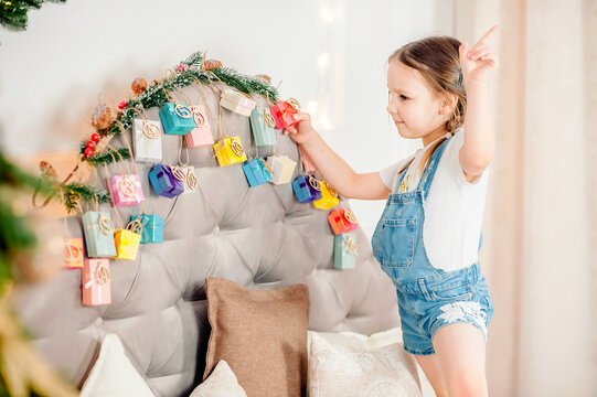 Little Girl Holding Present Box Handmade Advent Calendar At Home. DIY Xmas Advent Calendar For Kids