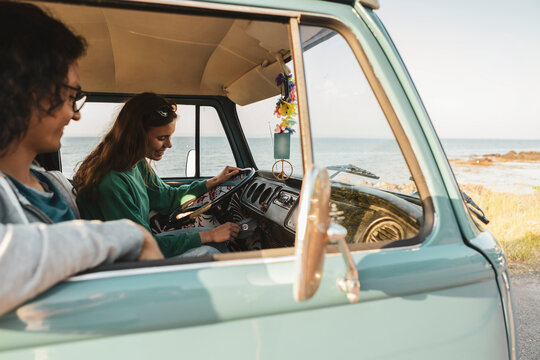 Woman starting engine of camping van sitting by male friend during road trip