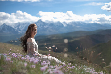 A beautiful girl in a gray dress walks against the backdrop of a mountain range. Wind in your hair....