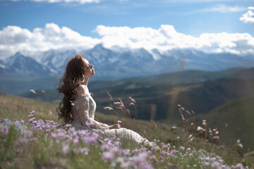 A beautiful girl in a gray dress walks against the backdrop of a mountain range. Wind in your hair. Kurai steppe. Severo-Chuisky Khrbet. Altai mountains. Photoshoot in a fairy-tale style.