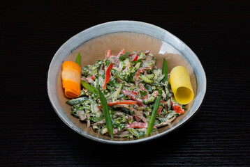Salad with vegetables, chicken and mayo on a black background
