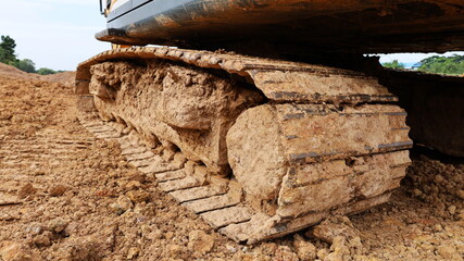 Dirty crawler backhoe. A crawler drive chassis of a heavy backhoe machine on a construction site....