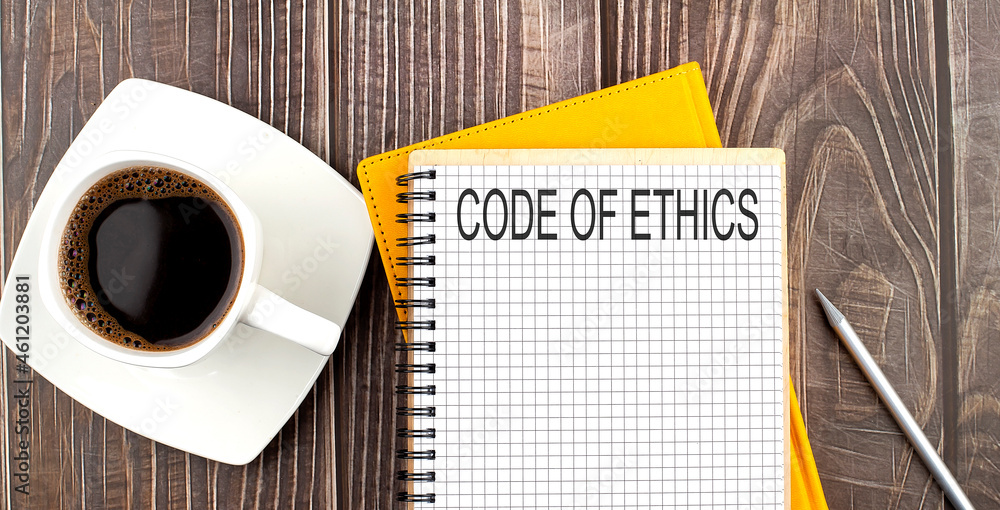 Poster code of ethics text on the notebook with coffee on wooden background