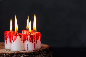 Burning Bloody candles on darkness background. White candles covered in red wax like blood drops....