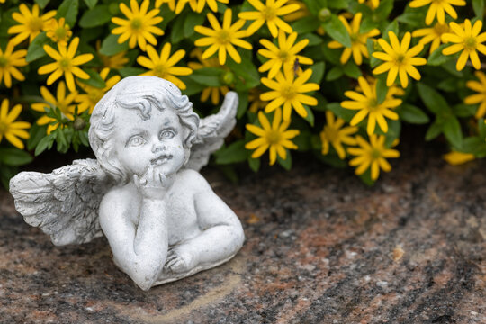 Angel on a tombstone with yellow flowers 