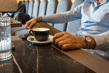 Man drinking coffee in the cafe bar, no face