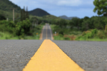 Close-up of a yellow traffic line Mountains and highways are out of focus.