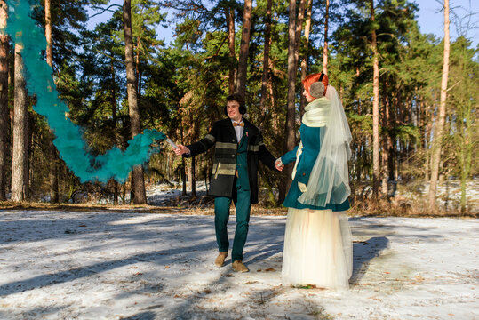 young couple in love in a pine forest holding a smoke bomb with green smoke