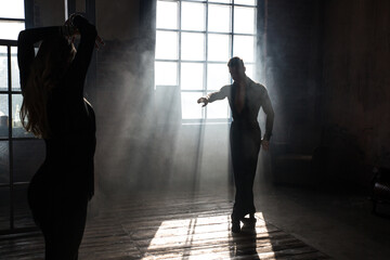 Couple of two professional ballroom dancers is dancing on loft studio. Beautiful art performance with heavy smoke. Sport life concept. Passion and emotional dance.