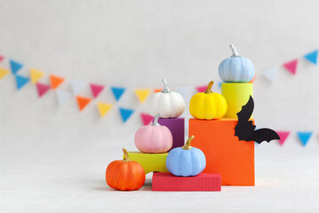 Colorful pumpkins on colourful podiums or pedestals with but over white background. Holiday Halloween party concept.
