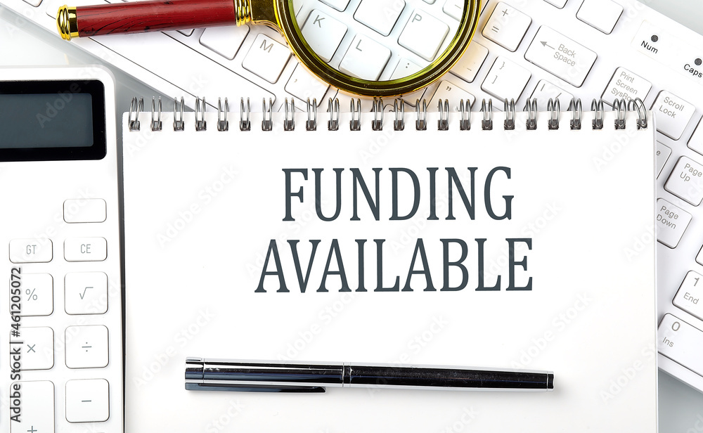 Poster funding available . text on notepad with calculator and keyboard,business concept