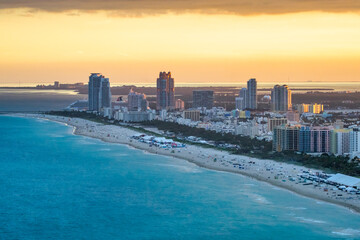 Aerial view of Miami skyline and tall skyscrapers from helicopter at sunset.