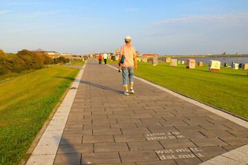 The beach promenade of Buesum in the evening light. People walking into the sunset. North sea - Germany