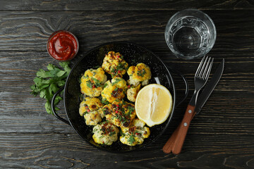 Concept of tasty food with baked cauliflower on wooden background