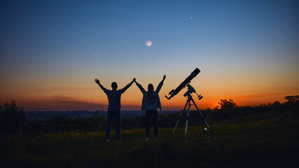 Fototapeta na wymiar Couple stargazing together with a astronomical telescope.