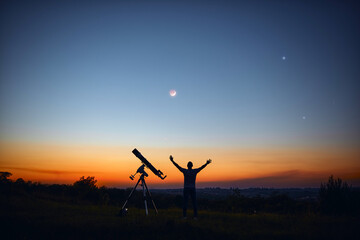 Fototapeta na wymiar Silhouette of a man, telescope and countryside under the starry skies.