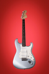 Naklejka premium Silver electric guitar isolated on red background.