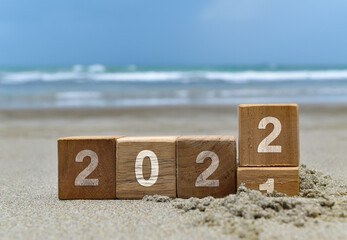 Happy new year 2022 background with wooden cube on the beach