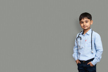 Cute small pakistani asian kid boy wear white shirt with stethoscope playing doctor, happy funny little mixed race preschool child pretending pediatri - obrazy, fototapety, plakaty