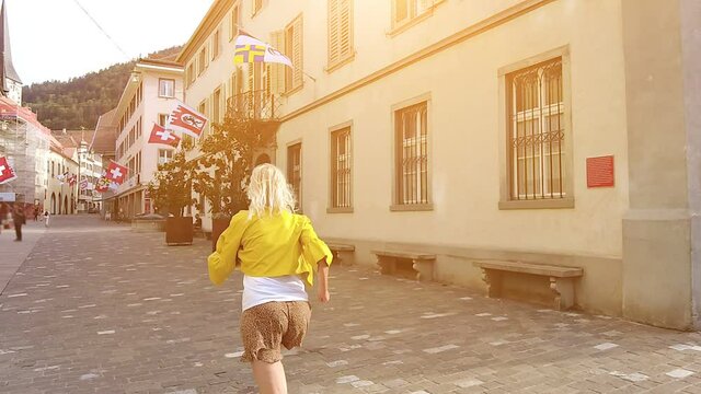 SLOW MOTION: Woman tourist running at sunset in the downtown roads of Chur city. Coira Swiss town in Grisons canton. Coira capital town of the Grisons Swiss canton of Switzerland.